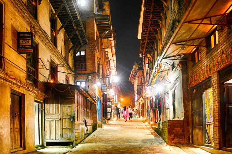 A Bhaktapur street at night, warm lights on old brick